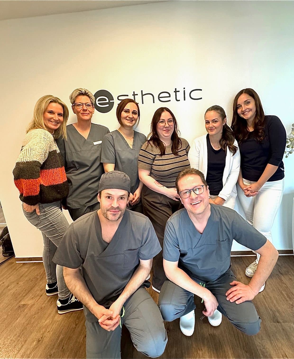 Das Team der e-sthetic® Privatklinik Essen vor dem Klinik-Logo: Dr. med. Daniel Talanow, Dr. med. Christian Josefs, Klinikmanagerin Janine Talanow und das Empfangs-, Station- und OP-Team